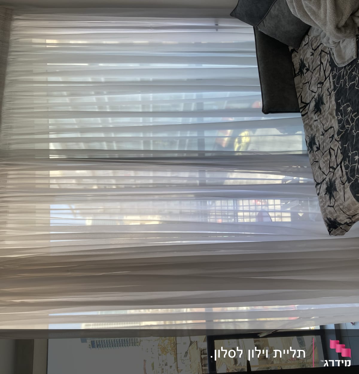 וילון לבן תלוי על חלון גדול